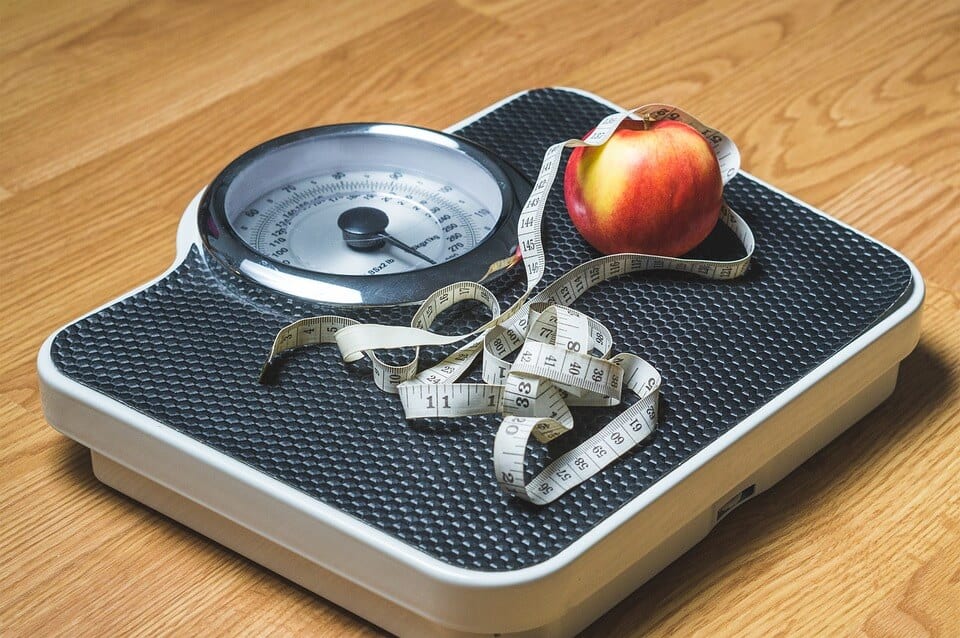measuring tape and an apple on top of a weight scale